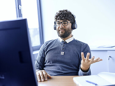 A Leadec employee wearing headphones during an online meeting.