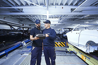 Two Leadec employees monitoring the automated conveyor technology using a tablet.