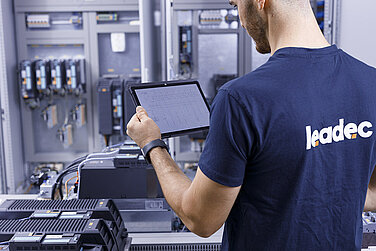 Leadec-Mitarbeiter mit einem Tablet bei der Überprüfung eines Schaltschranks.