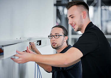 Two Leadec trainees during electrical installation.