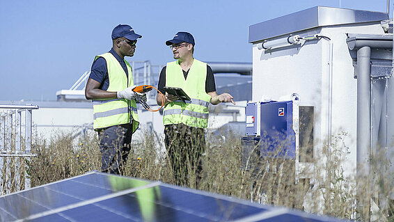 Zwei Leadec-Mitarbeiter auf einem Fabrikdach mit Photovoltaik-Modulen.