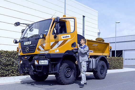 Ein Leadec-Mitarbeiter vor einem Streufahrzeug auf dem Werksgelände.