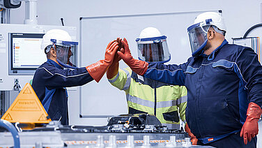 Leadec employees in protective giving high-five after successfully repairing a defective battery.