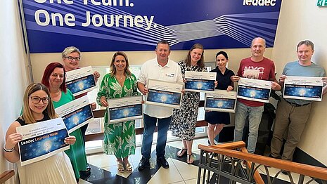 Group of Leadec colleagues holding posters of the Learning Week in their hands.