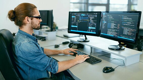 Man sits at the computer and programs.