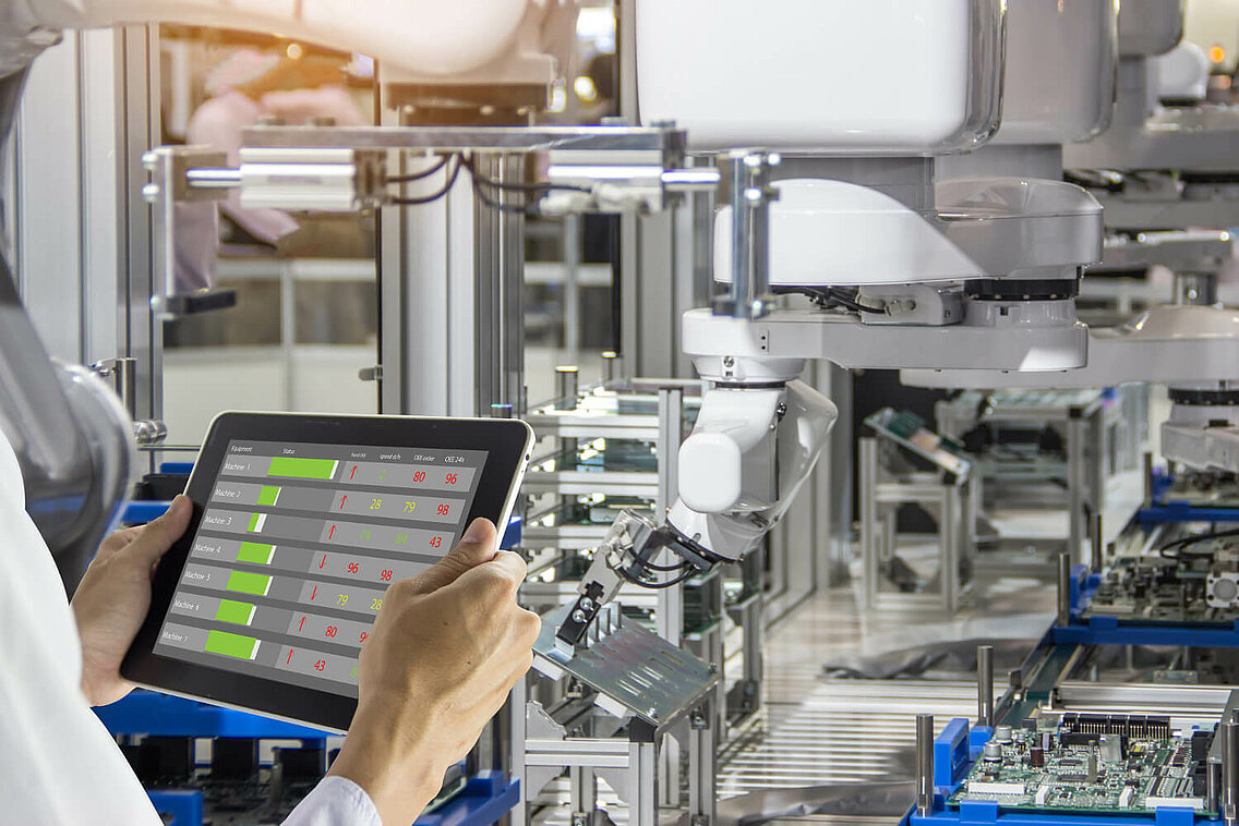 Mitarbeiter mit Tablet in der Hand prüft Performance einer Maschine.