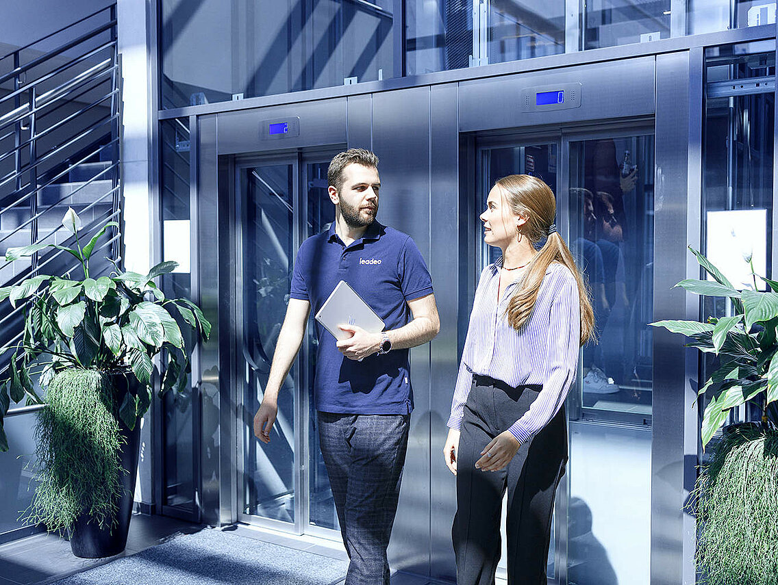 Two Leadec employees coming out of the elevator at the Leadec office in Stuttgart.