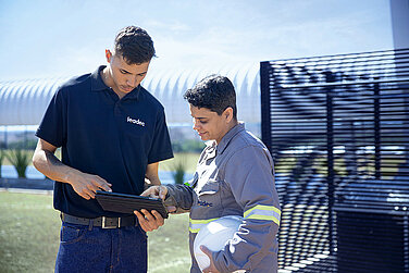 Two Leadec employees checking data on a tablet with Leadec.os.