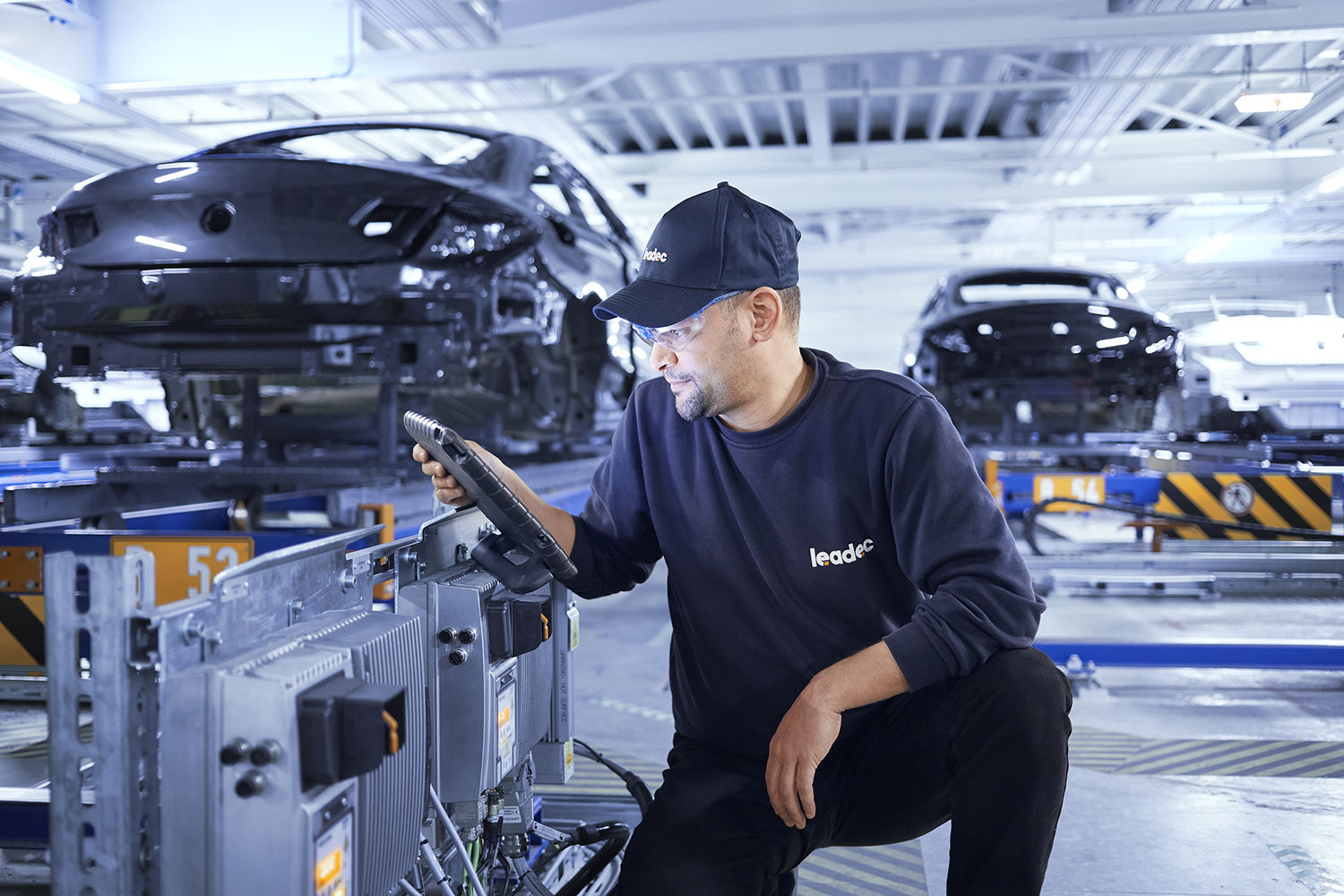 A Leadec employee configures an inverter at a conveyor belt.
