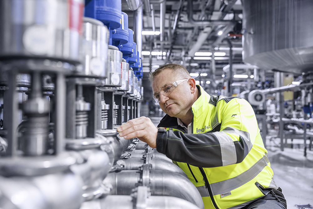 A Leadec employee inspecting pipes in a technical room.
